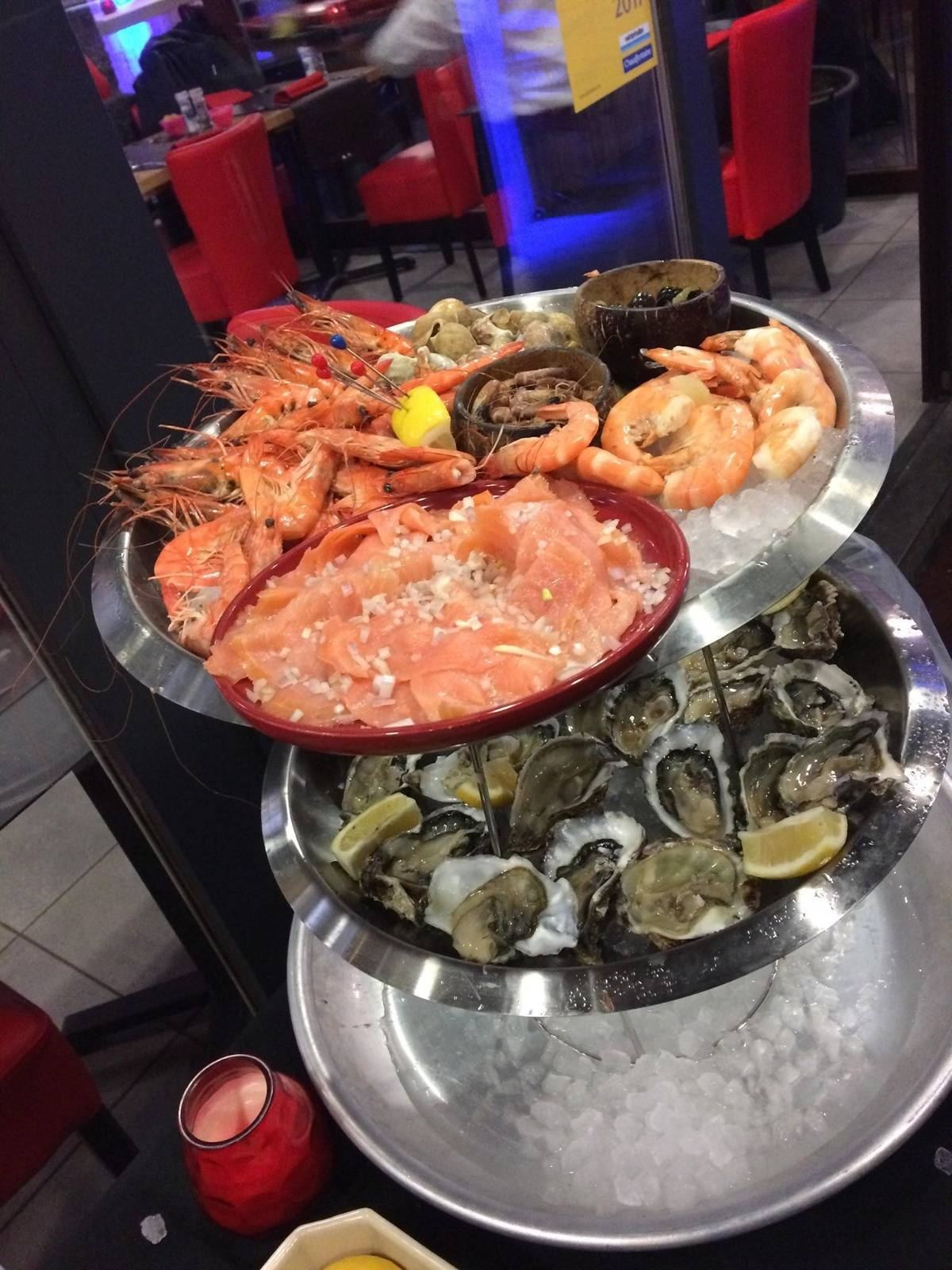 Plateau de fruits de mer sur glace, huîtres et crevettes, dans la salle aux chaises rouges