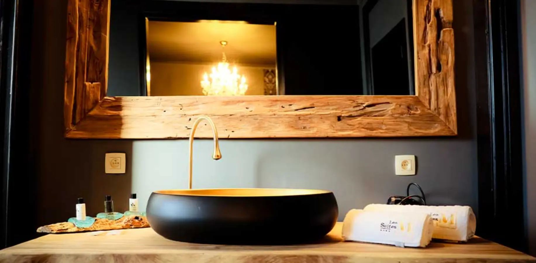Salle de bain d'une suite : vasque noire et miroir en bois