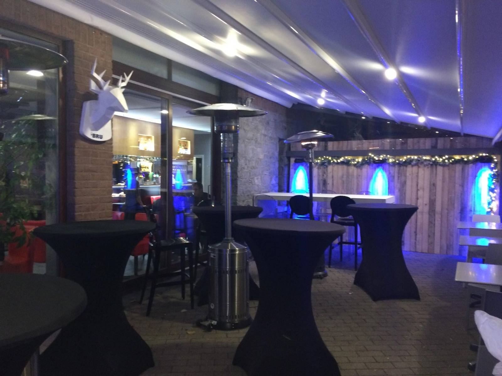 La terrasse couverte et chauffée de la Bistronomie M, le soir, tables hautes et parasols chauffants
